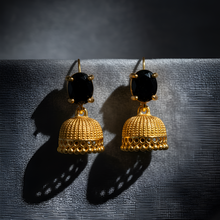 Gold earrings with black stones on a dark background