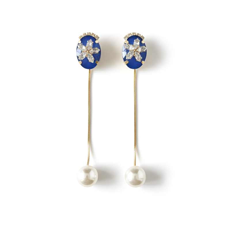 Pair of earrings with blue gemstones and pearl drops on a white background