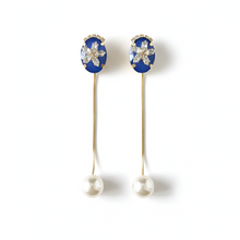 Pair of earrings with blue gemstones and pearl drops on a white background