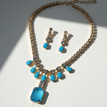 Necklace and earrings set with blue stones on a white background