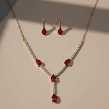 Jewelry set with necklace and earrings featuring red gemstones on a beige background