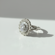 Silver ring with a large central gemstone on a light gray background