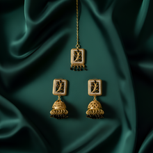 Gold earrings on a dark green fabric background