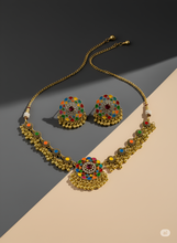 Gold necklace and earrings with colorful gemstones on a two-tone background