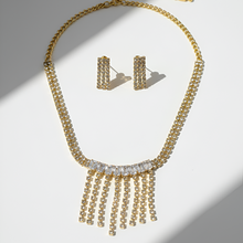 Gold necklace and earrings on a light gray background