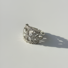 Silver ring with intricate design on a light gray background