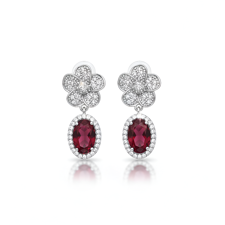 Pair of earrings with red gemstones and silver floral designs on a white background