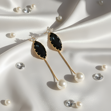 Gold earrings with black gemstones on a white fabric background