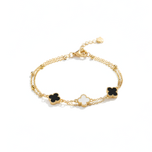 Gold bracelet with black flower charms on a white background