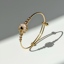 Gold bracelet with decorative elements on a gray background