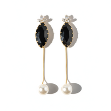 Pair of earrings with black gemstones and pearl drops on a white background