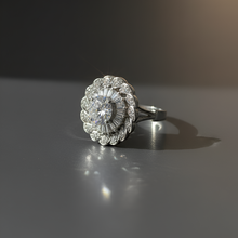 Silver ring with floral design on a reflective surface