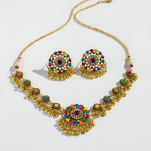 Gold necklace and earrings set with colorful gemstones on a white background