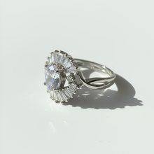 Silver ring with a large central diamond and smaller diamonds on a white background