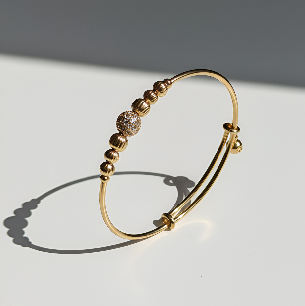 Gold bracelet with beaded design on a white background