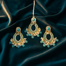 Ornate earrings with turquoise stones on a dark blue satin background