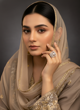 Woman wearing a beige embroidered saree with a dark background