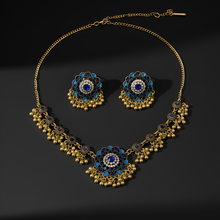 Gold necklace and earrings with blue and black gemstones on a dark background