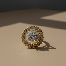 Gold ring with a central gemstone on a beige surface
