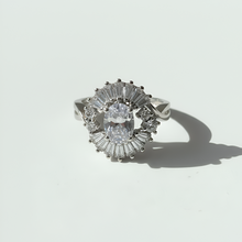 Silver ring with a central diamond and baguette-cut stones on a white background