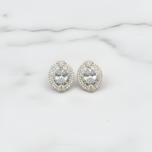 Pair of silver earrings with clear gemstones on a marble surface