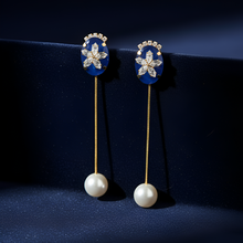 Pair of decorative earrings with pearl-like beads on a dark background