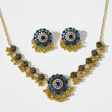 Gold necklace and earrings with blue and black stones on a white background