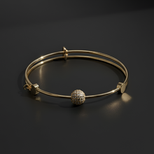Gold bracelet with a spherical charm on a dark background