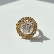 Gold ring with a large central gemstone on a white background