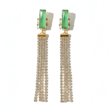 Pair of earrings with green tops and gold tassels on a white background